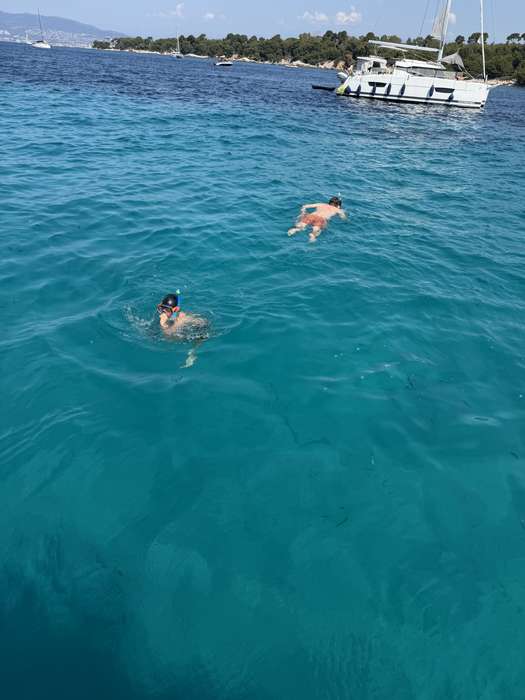 Baigneur dans une eau turquoise près d'un bateau
